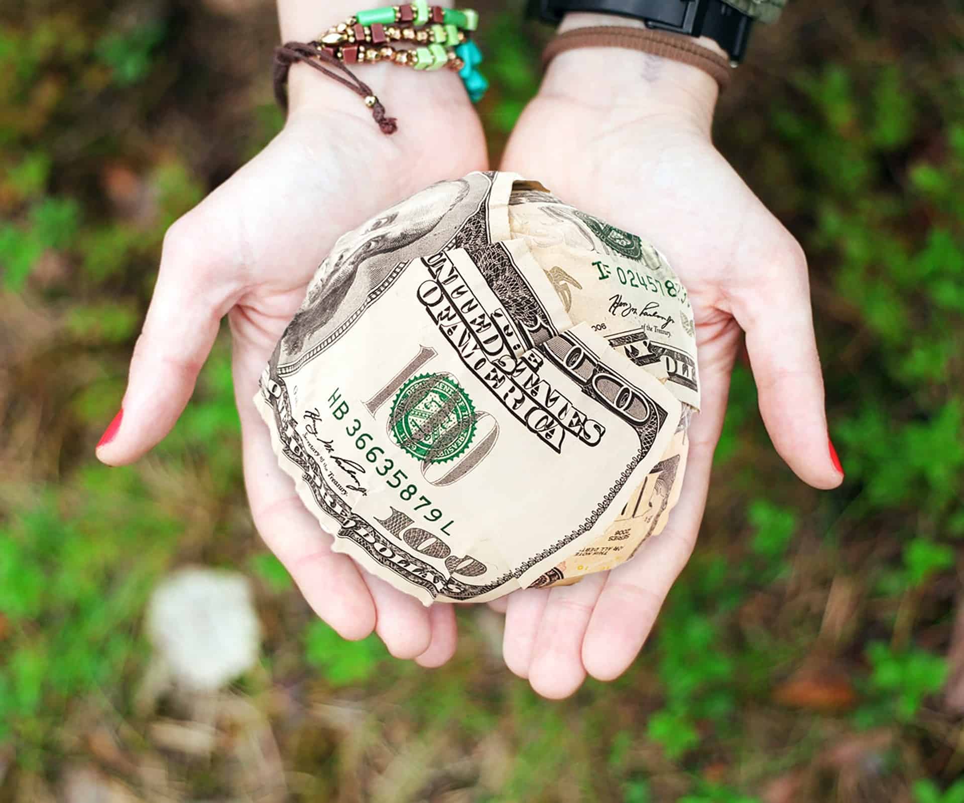 woman holding a ball made out of money